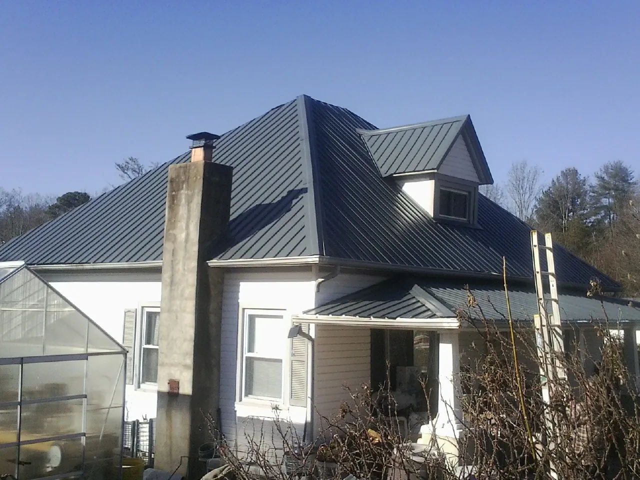 Dark blue standing seam metal roof on a white farmhouse with dormer — Slate & Tile Roof Repair by Roofing Brothers in Slade