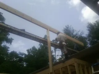 Carpenter setting a ridge beam over a new addition frame — Ice Dam Removal by Roofing Brothers in Slade