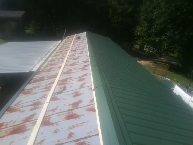 Old rusted panels beside newly installed green metal roofing — Wind Damage Roof Repair by Roofing Brothers in Slade