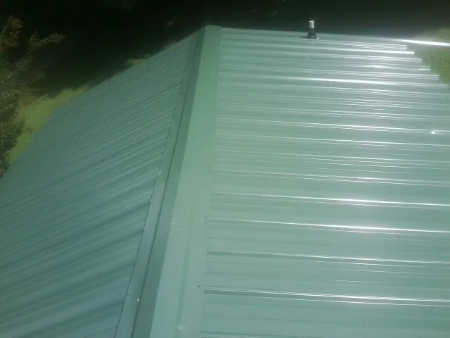 New green metal panels meeting at the ridge of a roof — Flat Roof Repair work by our crew in Slade