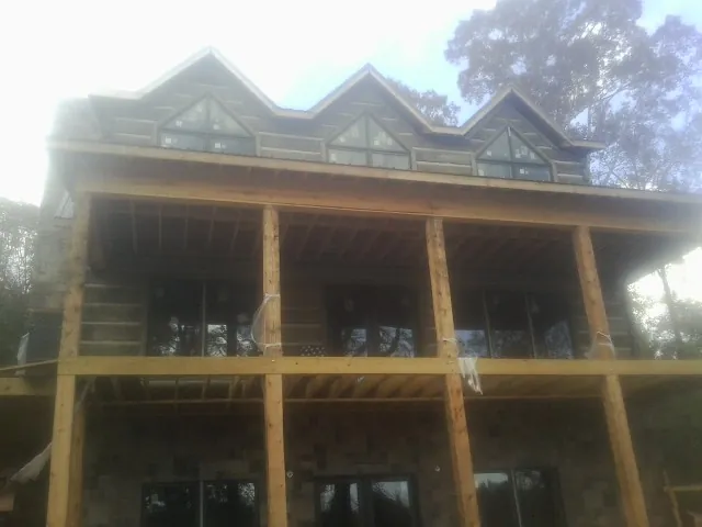 Dormers and porch framing on a large log home under construction — Roof Coating work by our crew in Slade