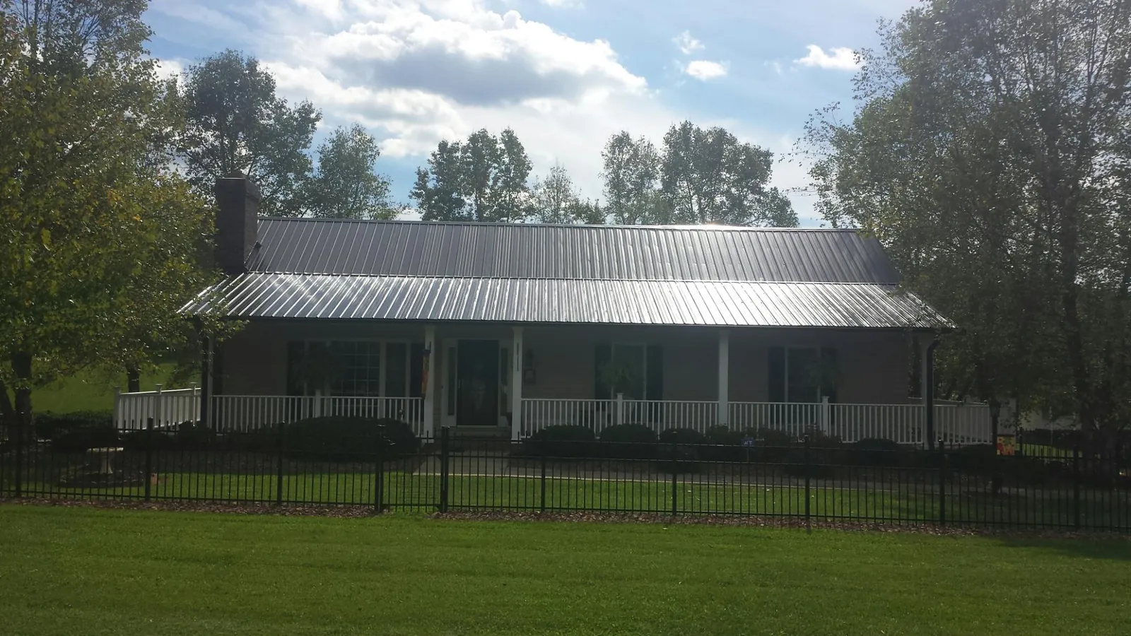Gray metal roof on a brick ranch with a full width front porch — Gutter Guard Installation work by our crew in Slade